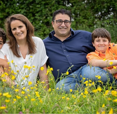 a family of three sitting on a field of flowers