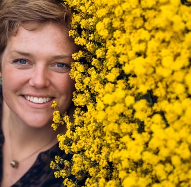 Billede af Gundas ansigt ved siden af et hav af gule blomster.
