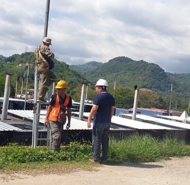 Engineers in hard hats inspecting an industrial generator farm with mountains in the background.