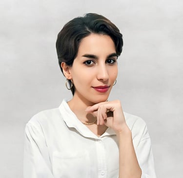 Portrait of a VISUALISE team member in a white shirt, gold necklace, and hoop earrings, against a neutral background.