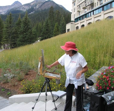 an artist painting outside with a mountain range in the background