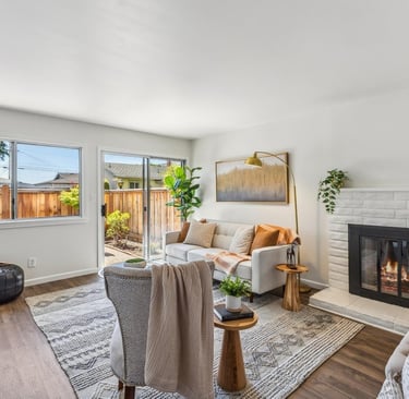 neutral color modern home staging of a living room with a fireplace, a couch, and gold color decors