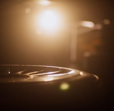 Cinematic close-up of a steel tongue drum with warm stage lighting and soft bokeh background.