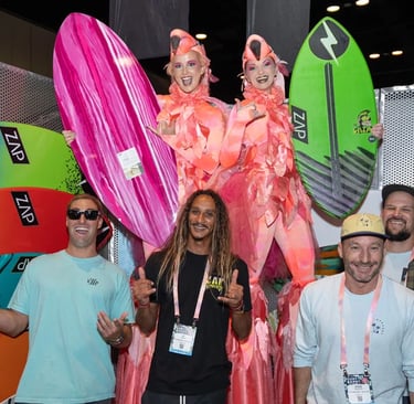 a group of people standing around two women in a costume in surf expo show