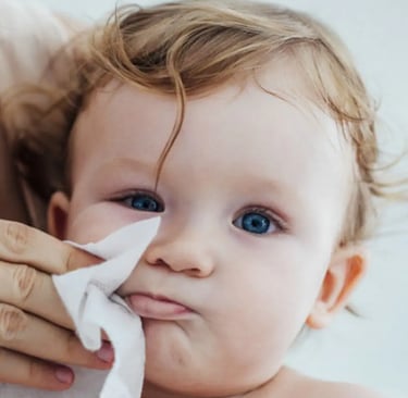 Cleaning a baby face with a wet wipe