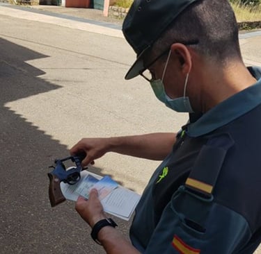 Guardia civil revisando documentación y un arma durante una inspección.