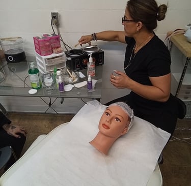 Esthetician student practicing facial waxing techniques in a college beauty salon training setting.