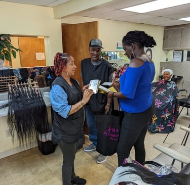 Student hair stylists discussing products and extensions with a teacher inside beauty school.