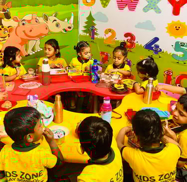 Preschool children in yellow uniforms eating lunch at a colorful table in a decorated classroom.