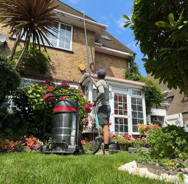 front of the house where a man holds a long pole while cleaning a gutter