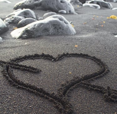 Heart drawn in dark sand on a California beach, symbolizing a romantic couples getaway