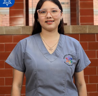 a woman in scrubs and glasses standing in front of a brick wall