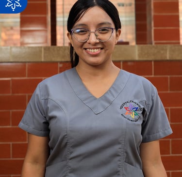 a woman in scrubs and glasses smiling for the camera
