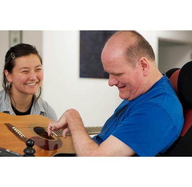 A disabled adult male learning to play the guitar