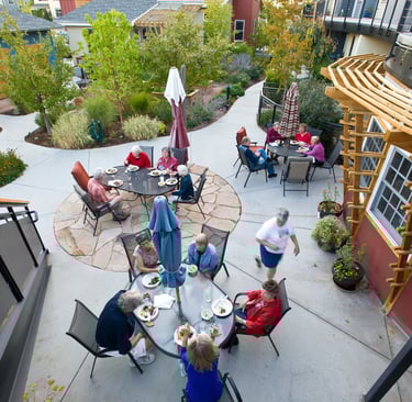 Groups of neighbors enjoying an outdoor meal at several tables on a patio.