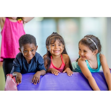 three young children in colorful gym attire are smiling and posing for a picture