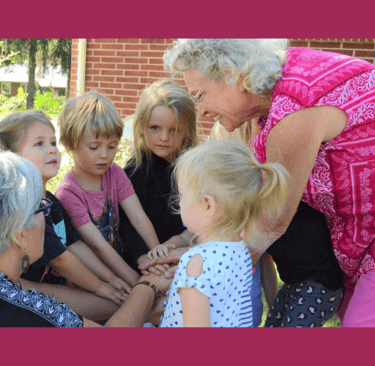An older woman helps out at the preschool