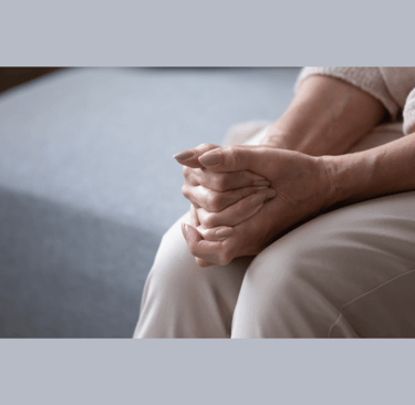 Older woman's hands clasped on her knees