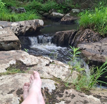 bare feet next to a babbling brook