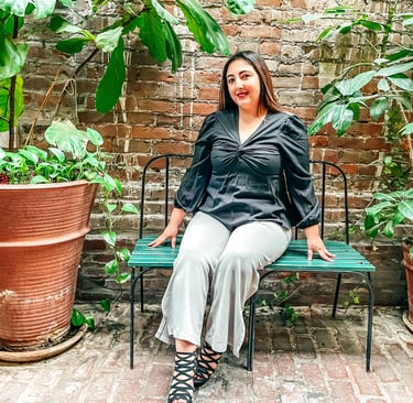 patricia sitting on a bench in a garden surrounded by plants