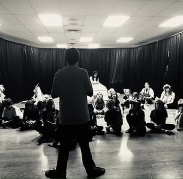 a youth director standing in front of a group of actors getting notes before the show.