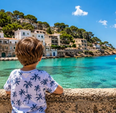 Young child looking out over the crystal-clear turquoise waters of Majorca, Spain, with a picturesqu