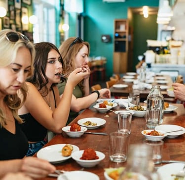 a group of people sitting at a table with plates of food