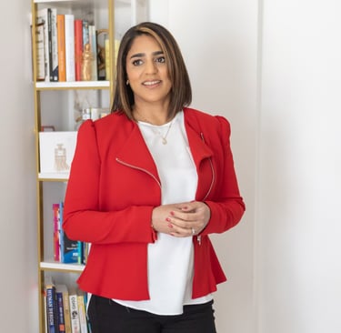 A photo of Anita wearing a white top, red jacket, and black trousers