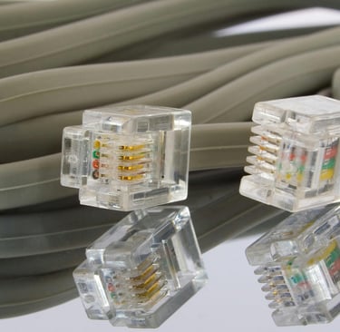 Conectores RJ45 y cable Ethernet gris reflejados sobre superficie, representando la transmisión de d