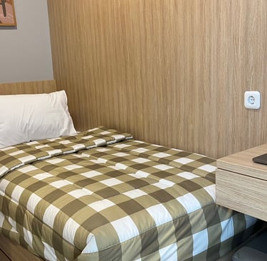 Kamar kos eksklusif Kos Si Bos Surabaya dengan single bed, meja belajar, lemari kayu, dan suasana modern minimalis