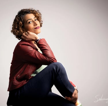 a corporate woman sitting on a stool with her hand on her chin