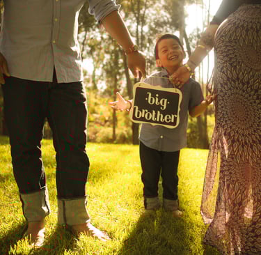 a family photo holding a sign that says big brother and the toddler big brother