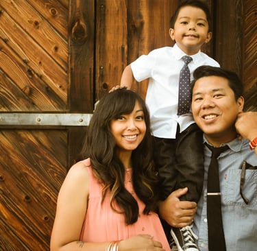 parents and son standing in front of wooden barn door photo