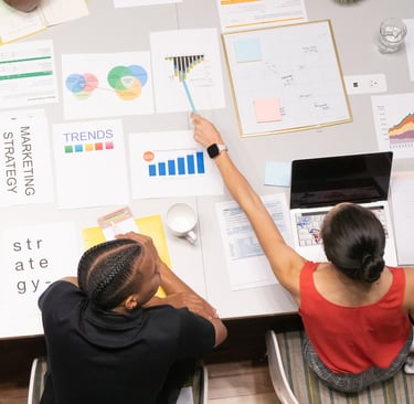two people sitting at a table with papers and papers