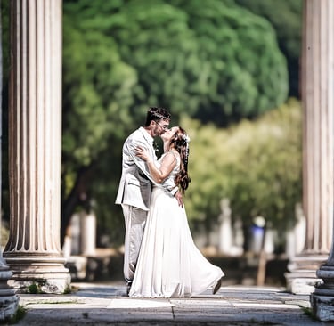 Romantisches Brautpaarshooting am Möhnesee – Hochzeitspaar küsst sich zwischen historischen Säulen.