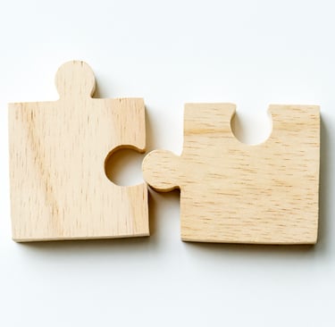 Two wooden puzzle pieces connecting together on a white background, representing teamwork and strategy.