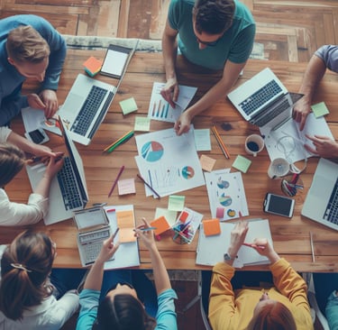 Aerial view of a creative team collaborating on a marketing project with laptops and data charts.