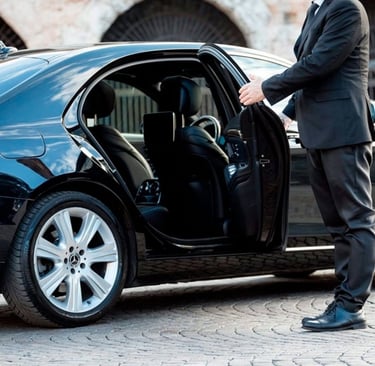 a man in a suit and tie is standing in front of a car