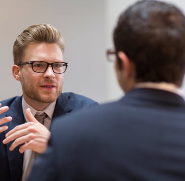 a man in a suit and tie is talking to another man