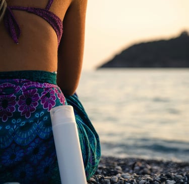a woman sitting on a beach with a bottle of sunscreene