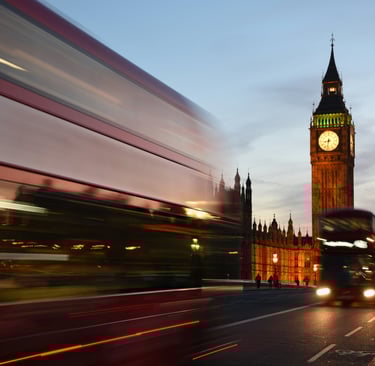 a bus driving down a street with a clock tower in the background