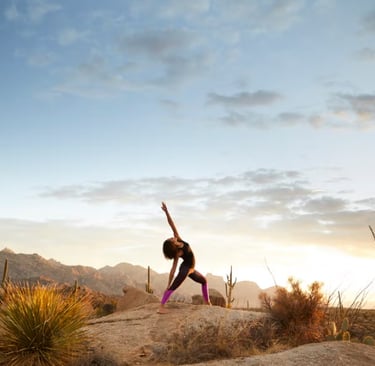Woman doing yoga at sunrise in the desert mountains during a wild feminine awakening retreat
