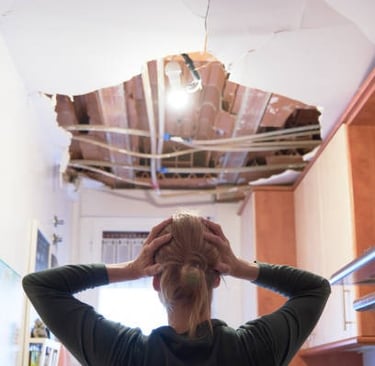 woman holding her head looking at damage to house from a leak