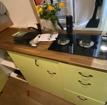 Camper van kitchen featuring a wooden countertop with a two-burner gas stove and yellow cabinets.