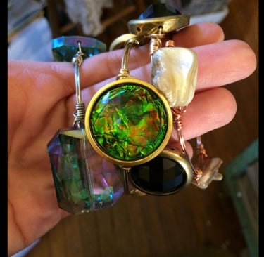 a person holding a necklace with a green glass pendant