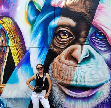 a woman standing in front of a mural of a monkey