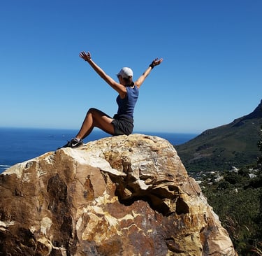 a woman sitting on a rock with her arms up and arms up