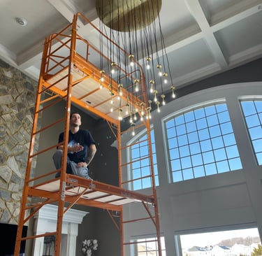 Man on a scaffold inspecting a high-end chandelier installation