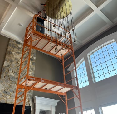 man on a scaffold installing a high-end chandelier