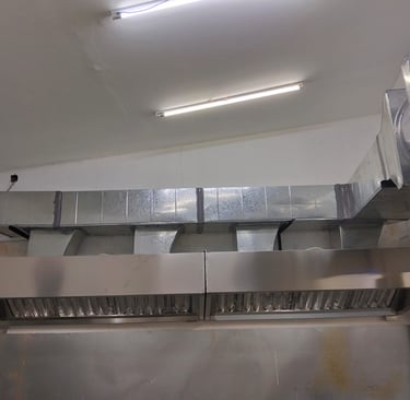 Industrial stainless steel commercial kitchen exhaust hood with silver ventilation ducting